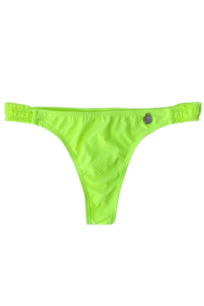 Bombacha Yellow Fluo con textura gofrada y frunce cola less de Alitas Bikinis. Bikini amarillo neón vibrante con laterales elásticos fruncidos que no marcan. Moldería cavada de tiro medio con dije plateado sobre fondo blanco.